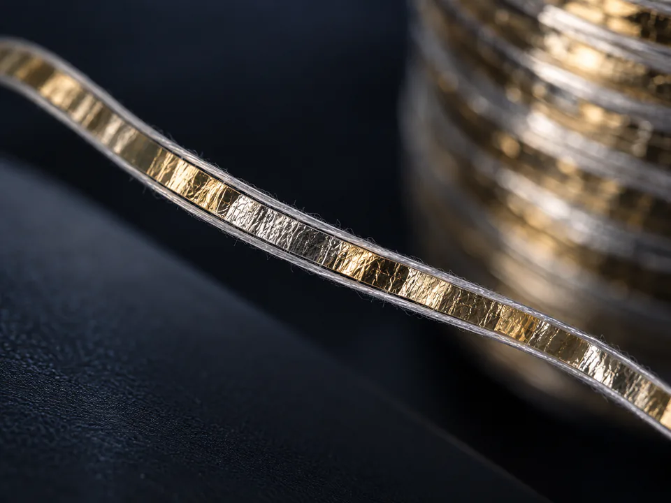 Gold metallic film supported by two fine textile filaments for MX Type yarn